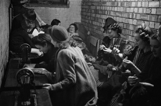 London Blitz Bermondsey 1941.  Sewing in a craft lesson given by London County Council (LCC) teachers at an air raid shelter.  X..png