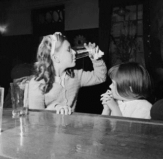 Jamaica Road, two young girls sitting at the bar of the Royal George pub in Rotherhithe, 1954, a children's Club Party..png