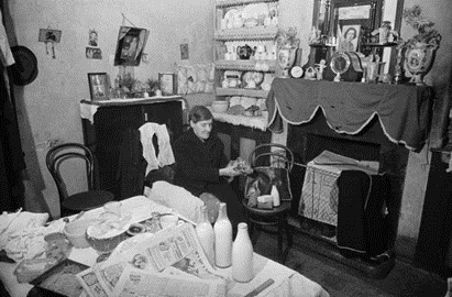 Christmas Street 1946, Mrs Francis sits in her cluttered living room. X.png